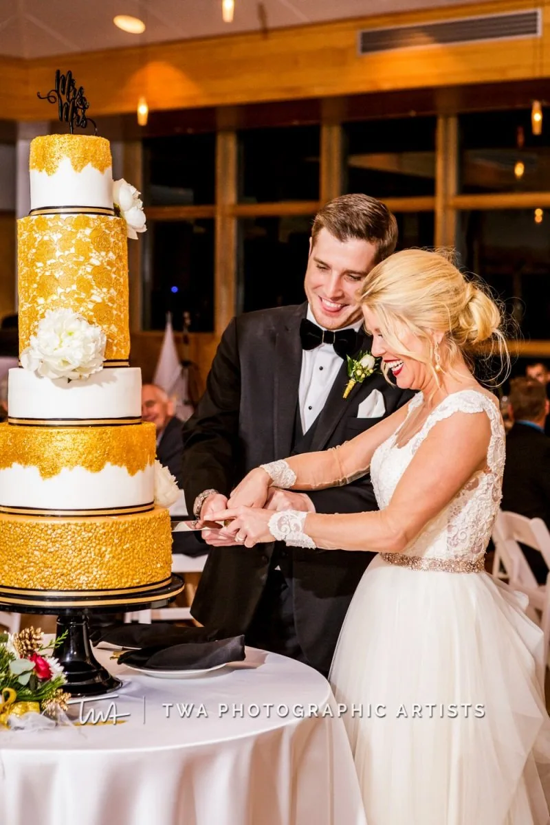 A man and woman at their reception, cutting a wedding cake