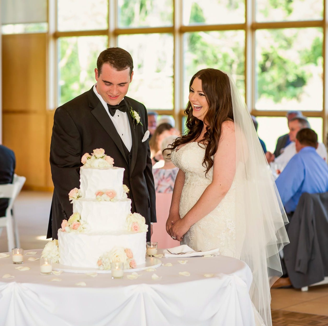 Wedding couple smiling and laughing while cutting the cake after their wedding ceremony and during their reception at danada house.