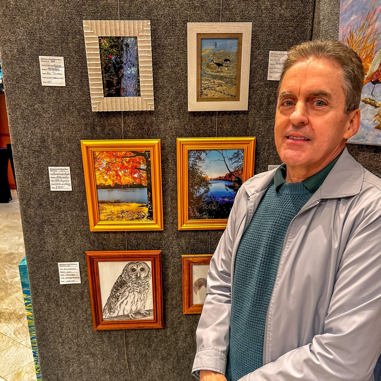 Artist posing with his photography display panel at the show